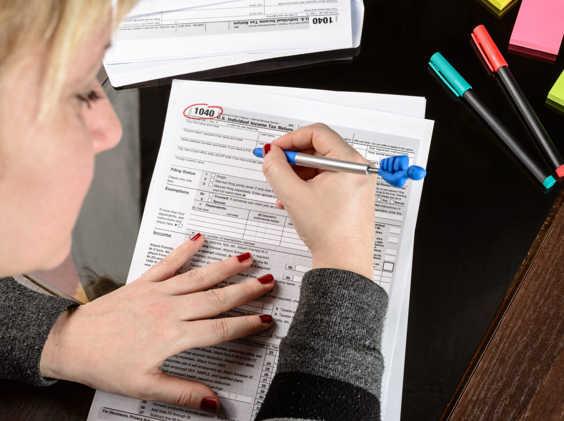 Woman fills the tax form, working with tax documents. Form 1040 Individual Income Tax return form. United States Tax forms. American blank tax forms. Tax time.